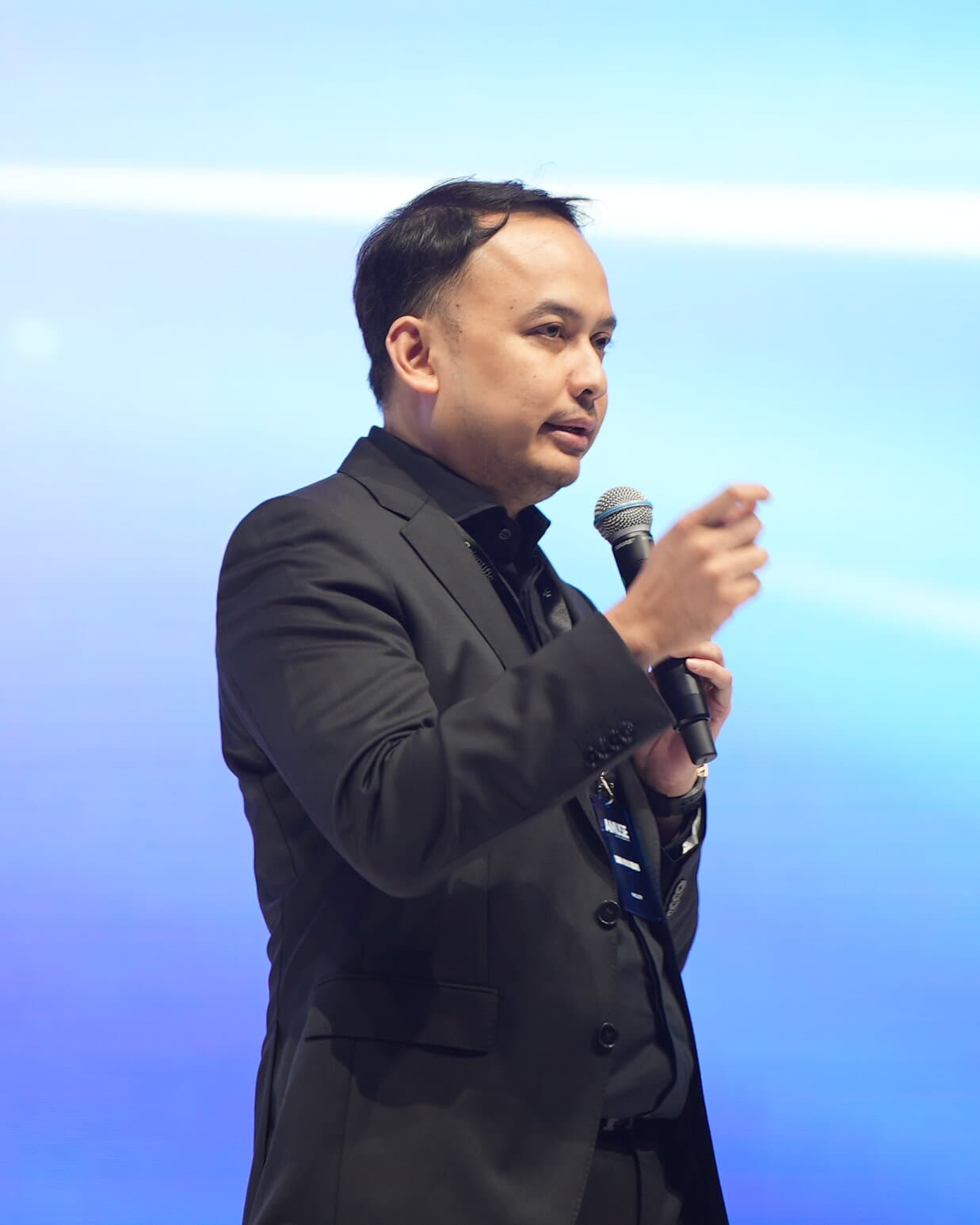 Dr. Danu speaking on stage with a microphone at a congress